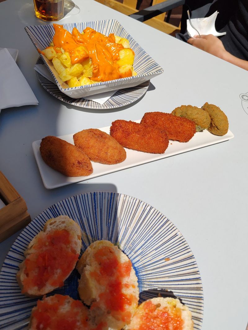 Patatas bravas, croquetas caseras y pa amb tomàquet en la terraza