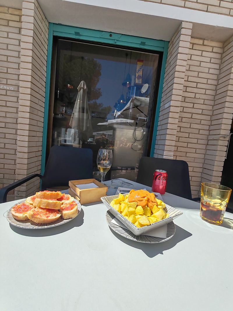 Mesa en la terraza frente a la fachada de ladrillo y el marco turquesa